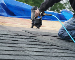 handyman using nail gun to install shingle to repair roof